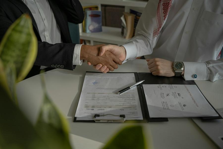 Dos personas se dan la mano sobre un contrato
