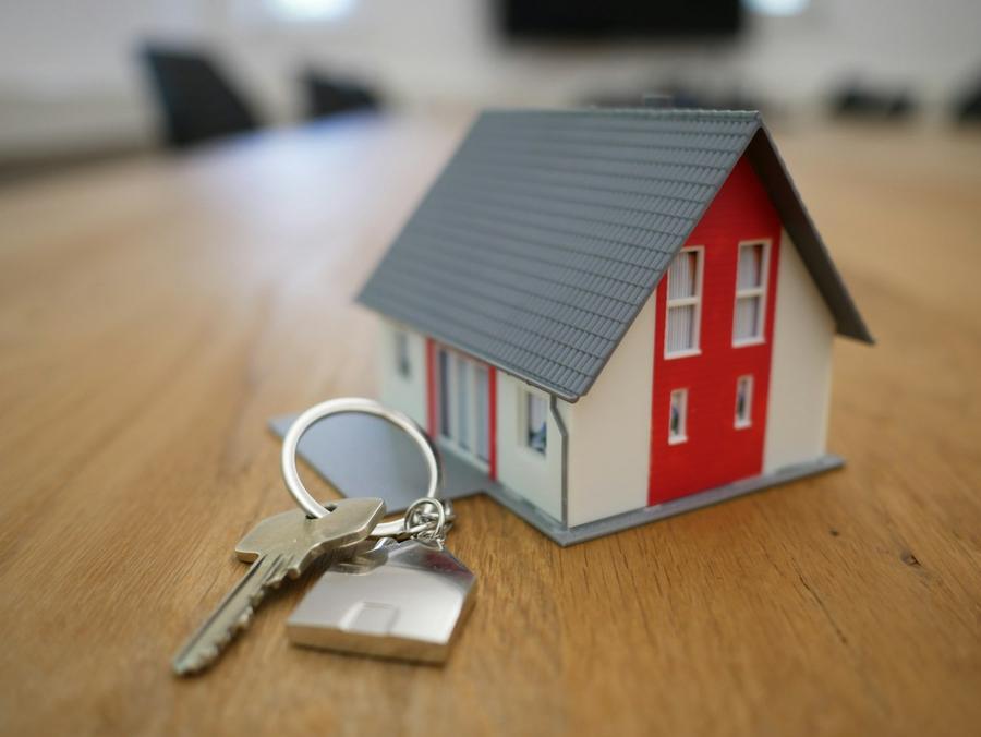 Casa en miniatura con llaves sobre una mesa